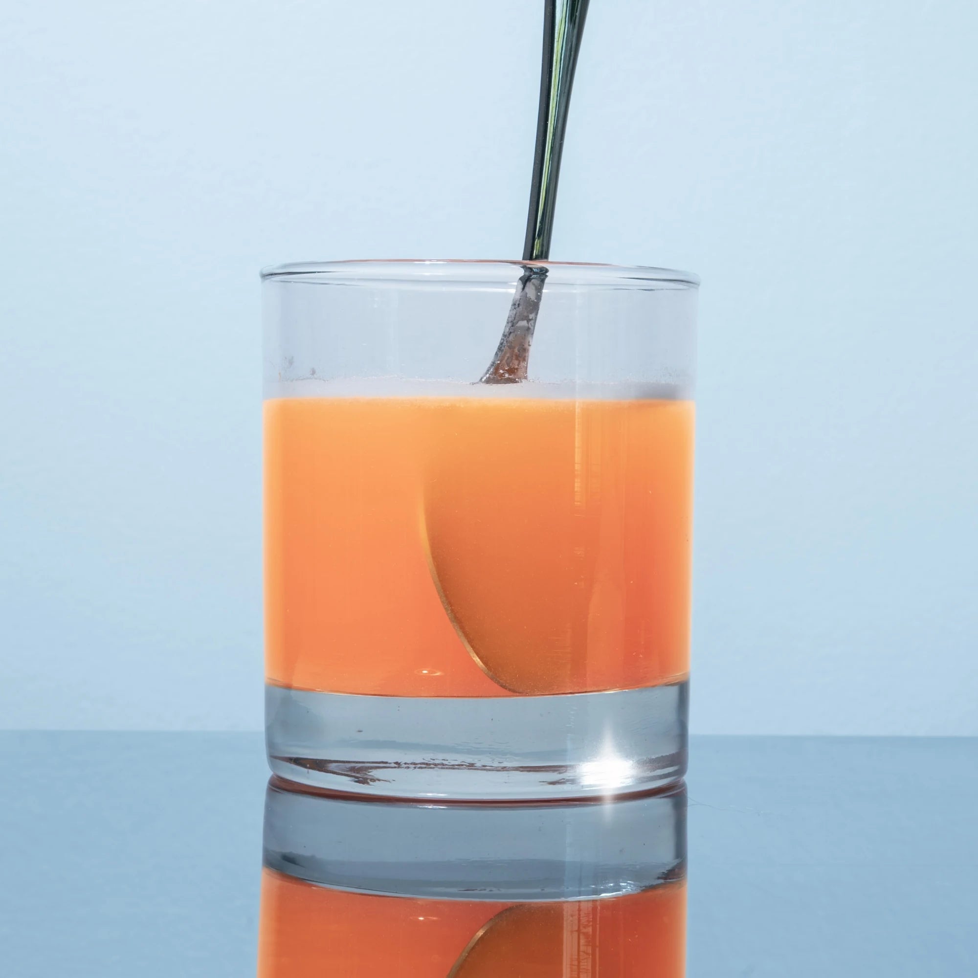 Magic Scoop Electrolytes + Creatine Orange Creamsicle mixed into a glass of water, stirred with a spoon