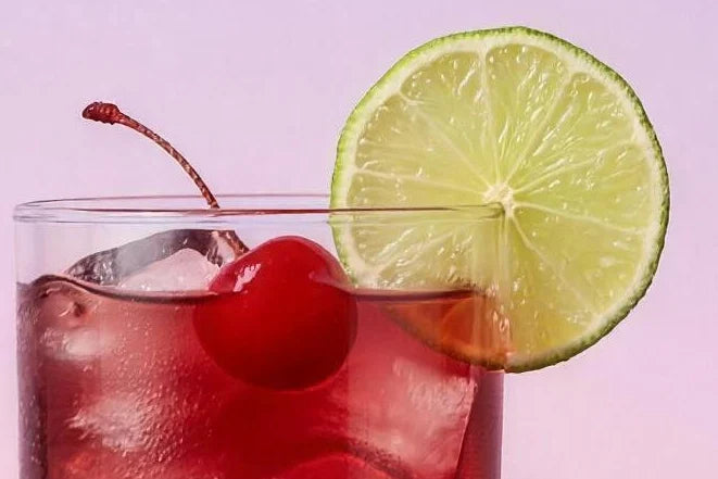 A tall glass of deep red cherry limeade Magic Scoop Electrolytes + Creatine with a cherry and lime.